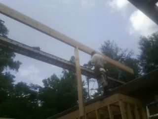 Carpenter setting a ridge beam over a new addition frame — Ice Dam Removal by Roofing Brothers in Ewing
