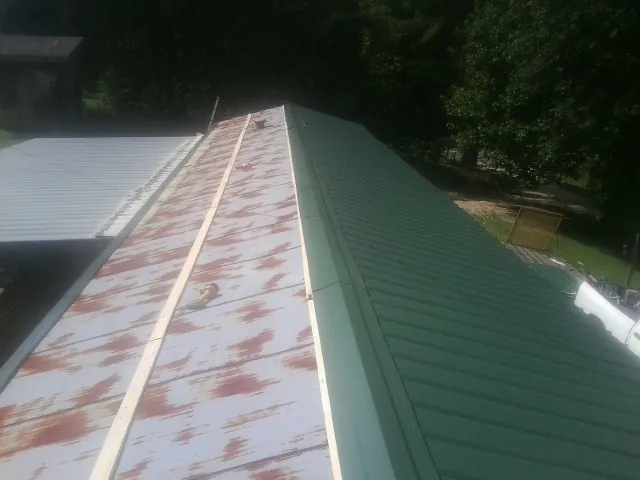 Old rusted panels beside newly installed green metal roofing — Wind Damage Roof Repair by Roofing Brothers in Ewing