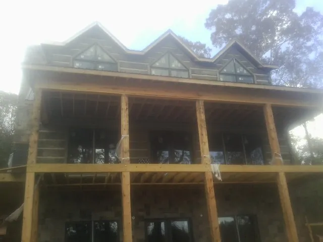 Dormers and porch framing on a large log home under construction — Roof Coating work by our crew in Ewing