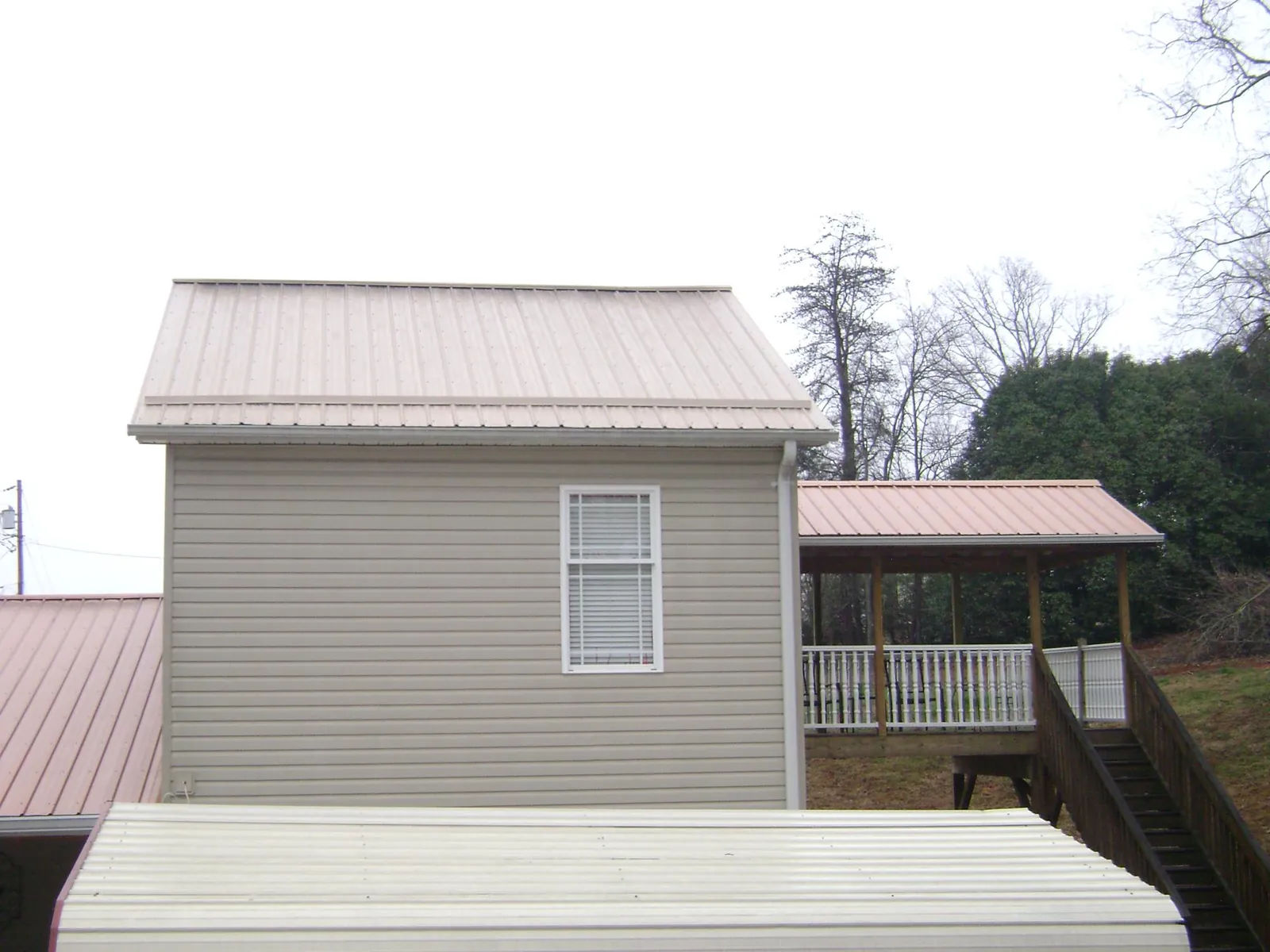 Tan metal roofs on a two story addition and attached porch, from a Roof Replacement job in Ewing